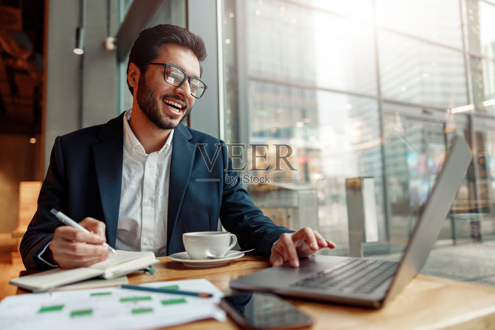 印度商人工作日在咖啡馆用记事本做笔记。模糊的背景照片摄影图片