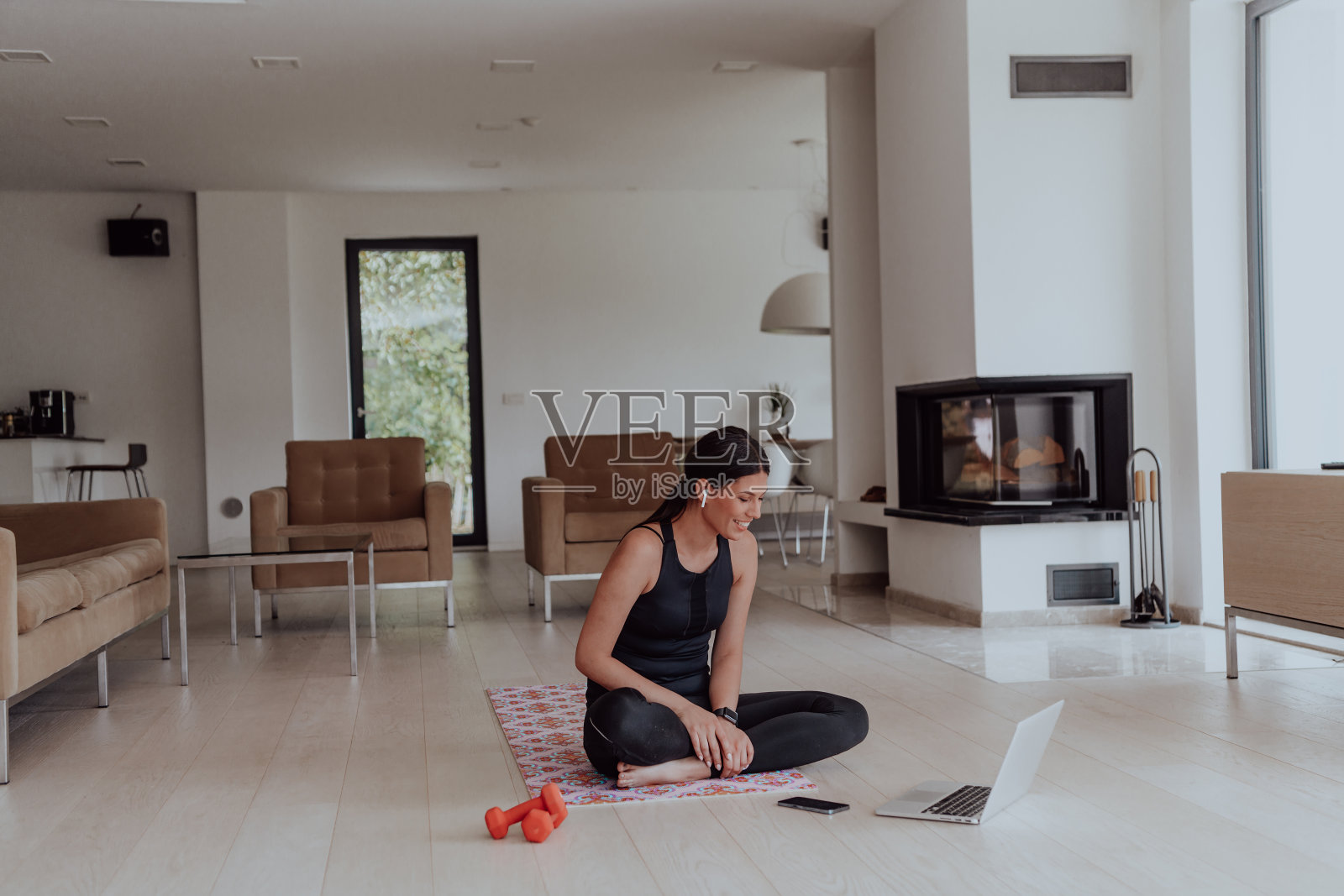 年轻美丽的女性与教练通过视频电话会议在明亮阳光的房子。健康的生活方式，幸福和正念概念。照片摄影图片