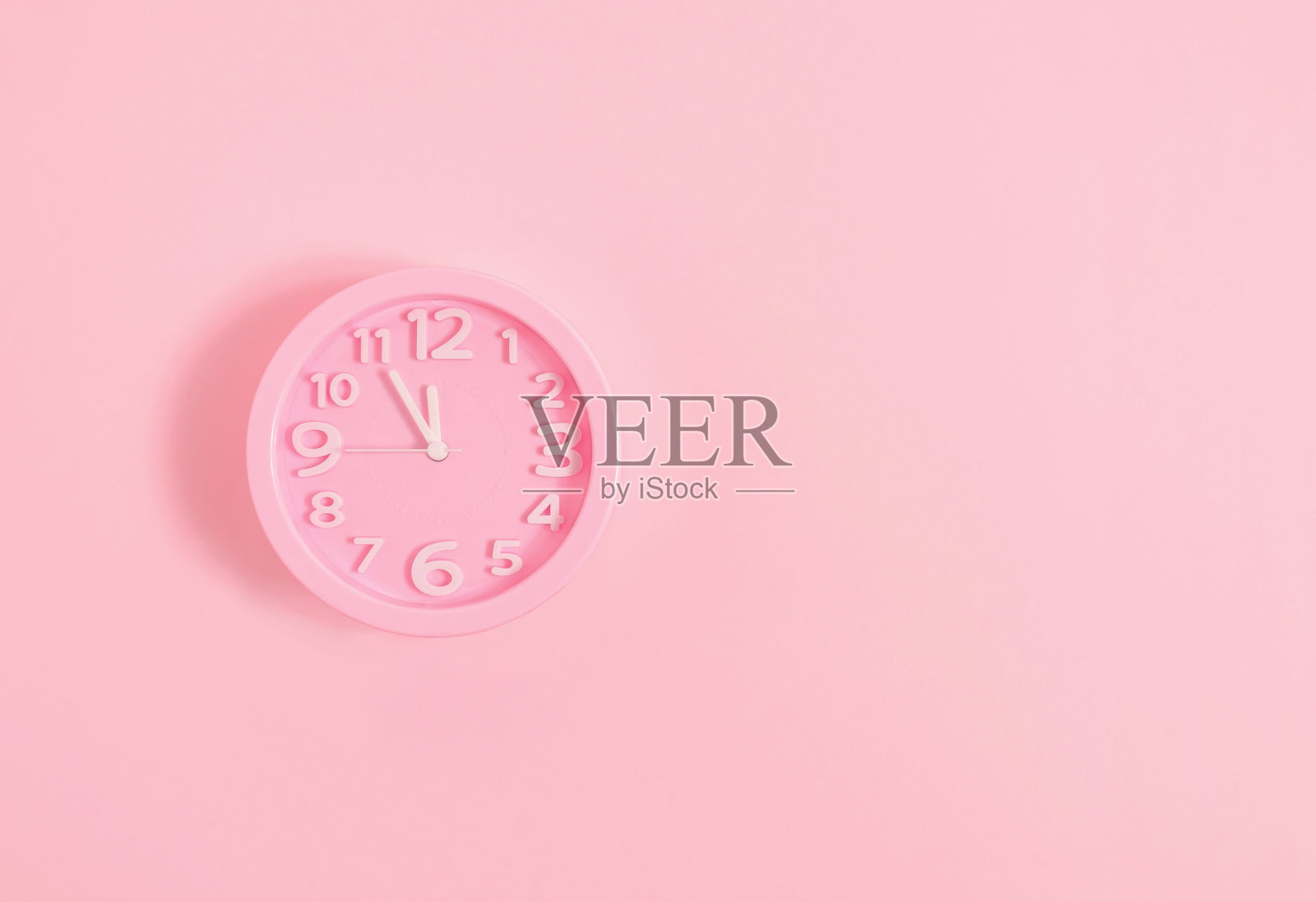 粉彩的粉色墙壁上的闹钟在粉红色的墙壁上，平安夜或新年的概念照片摄影图片