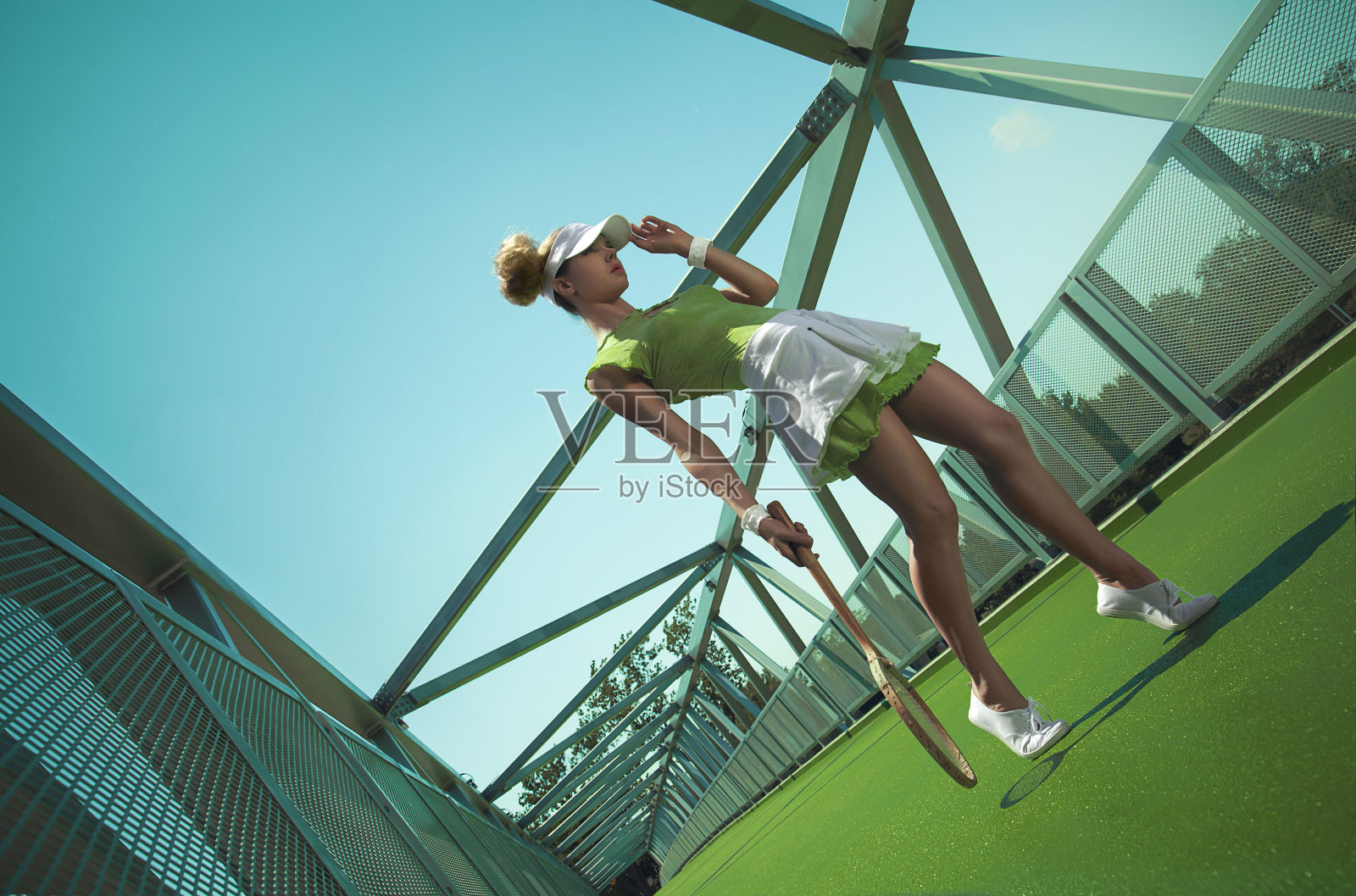 年轻女子梳着两个发髻在城市球场打网球照片摄影图片