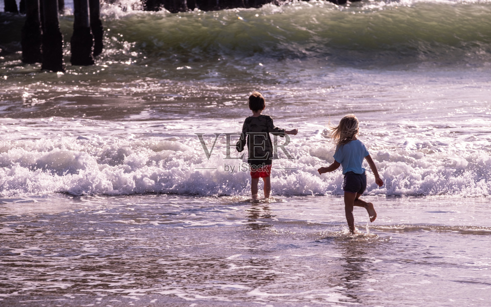 孩子们在海滩上奔跑，打破海浪，大海，大海照片摄影图片