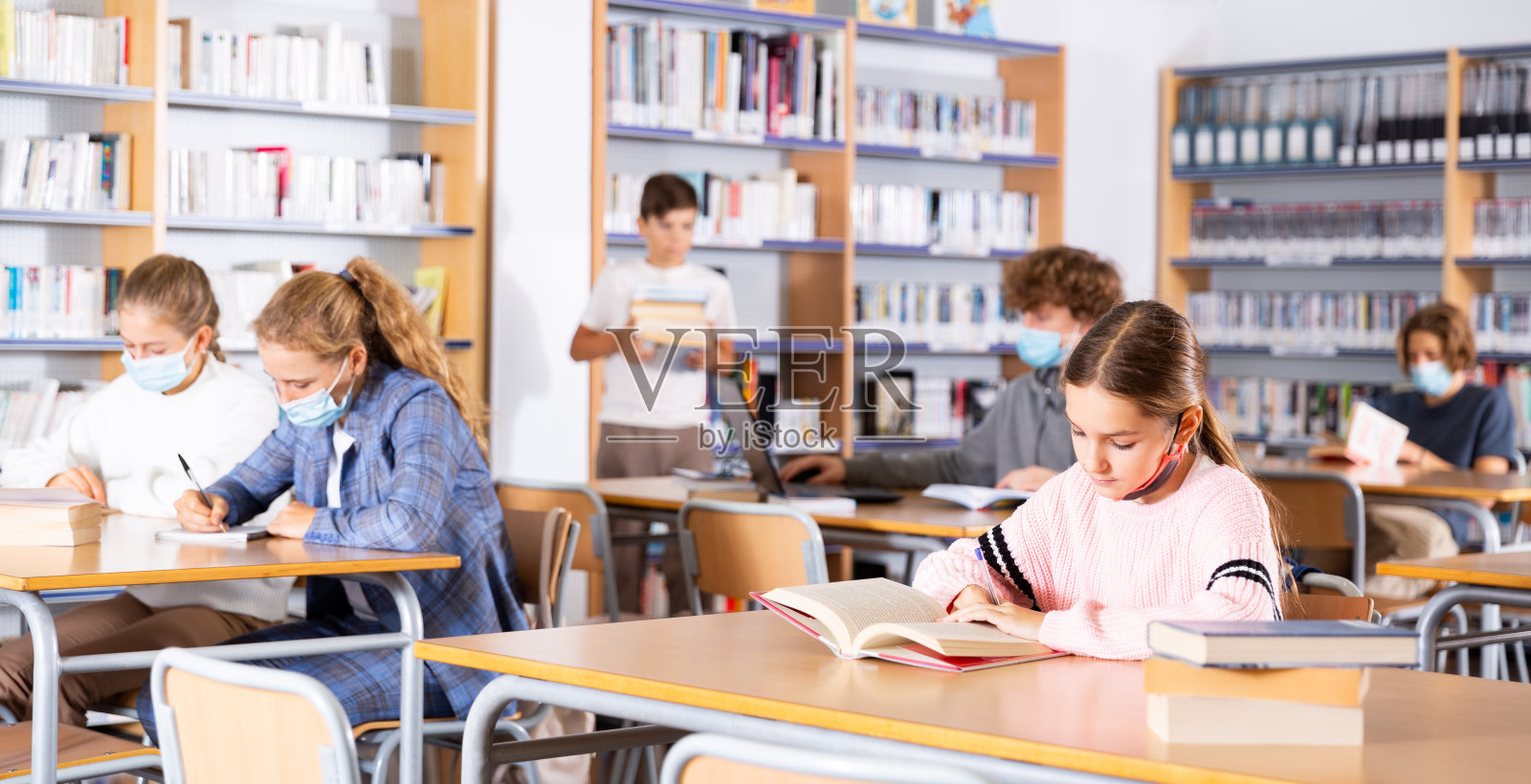 全神贯注的学生戴着面具写一篇总结，学习新材料照片摄影图片