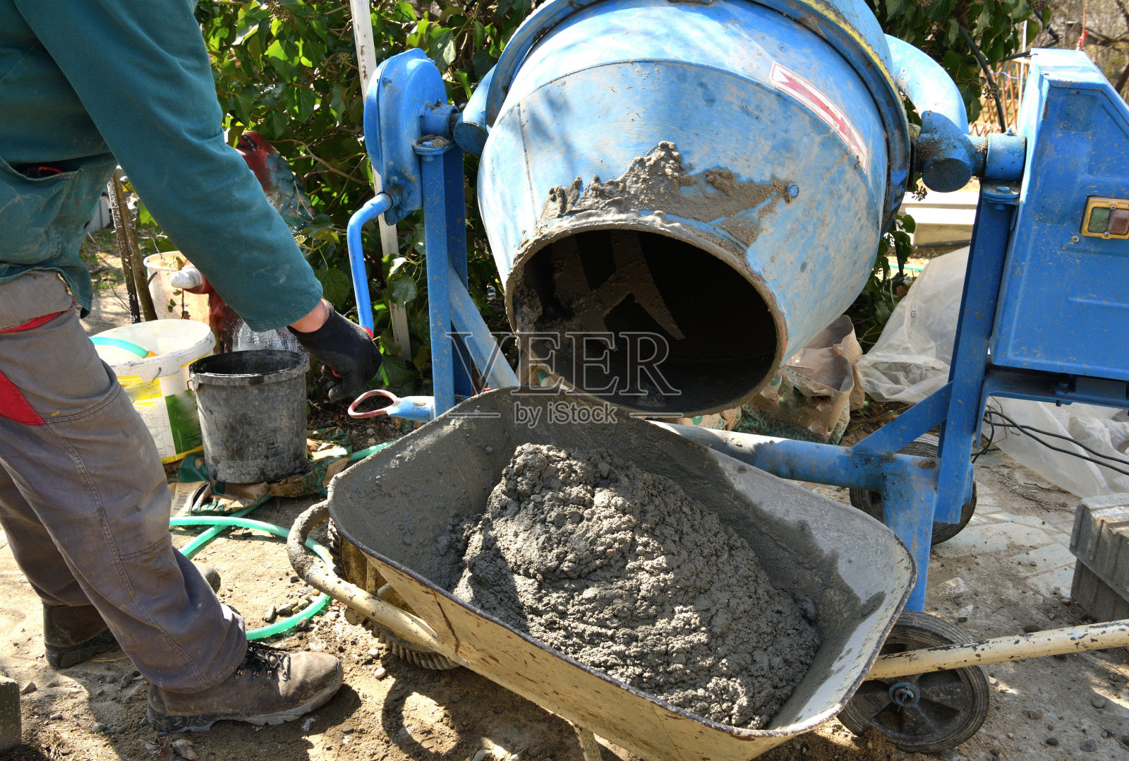 一位砖瓦工将混凝土从调温器中倒入村里传统的独轮手推车中照片摄影图片