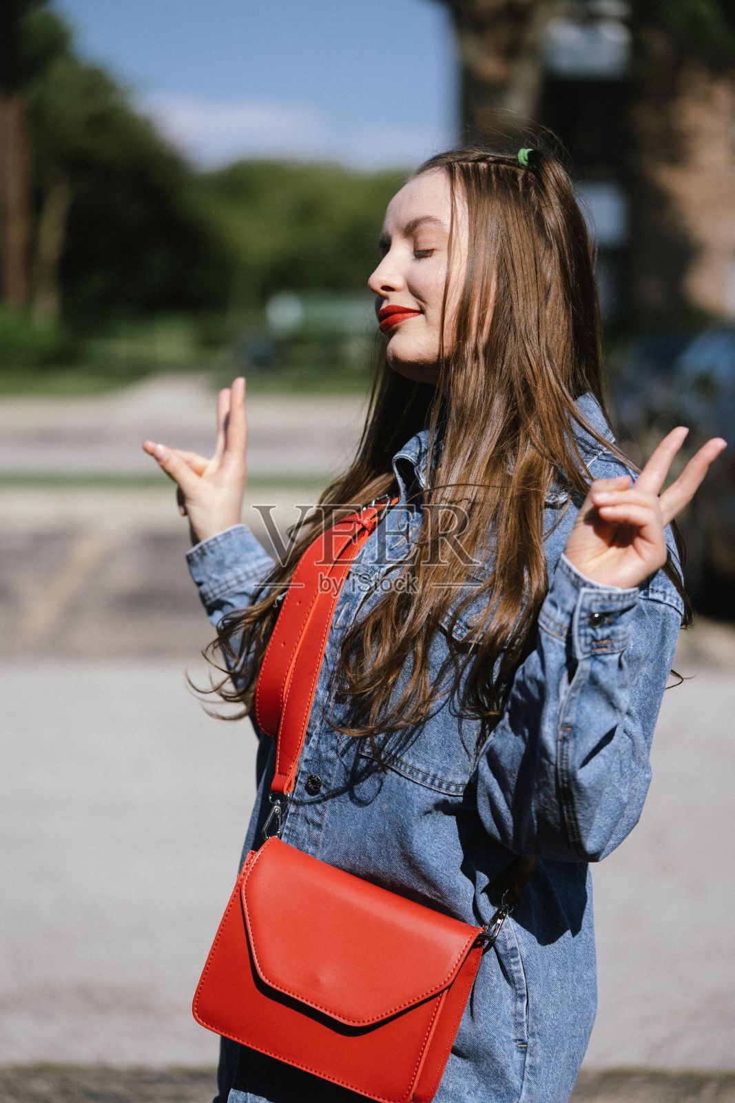 一名白人妇女在户外摆姿势并展示和平标志的垂直镜头照片摄影图片