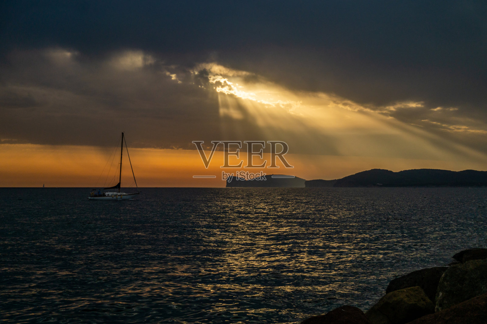 在撒丁岛阿尔盖罗，海上的帆船在日落的天空中明亮的阳光照片摄影图片
