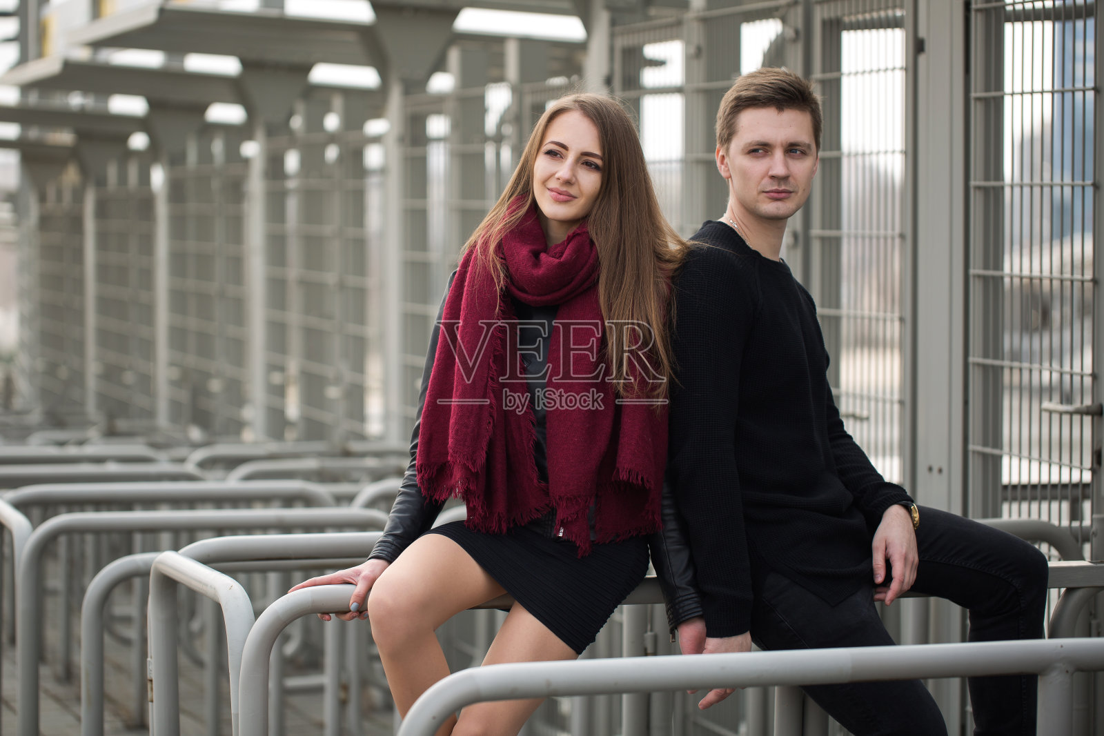 一对年轻的男女坐在栏杆上照片摄影图片