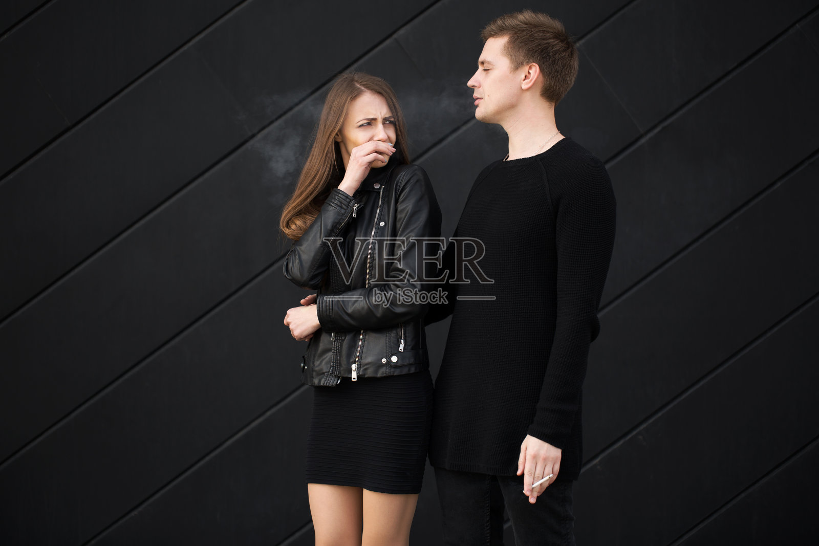 被动吸烟的概念。一名妇女遮住了她的脸，不让她吸烟。不吸烟的女人要求她的男人戒烟照片摄影图片