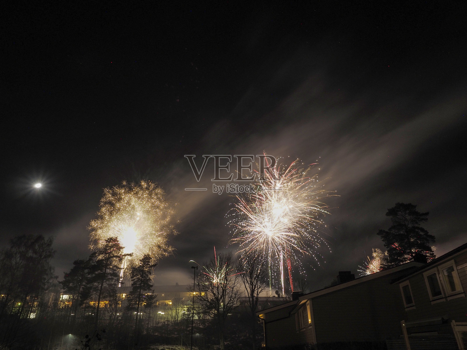 烟花，在屋顶上方的小山上，挨着月亮照片摄影图片