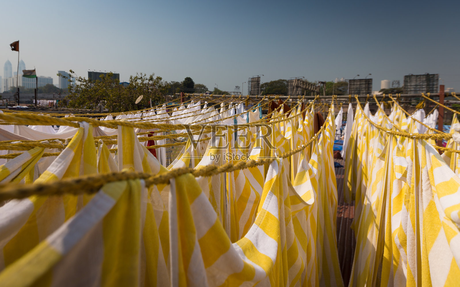 黄色和白色的织物床单挂在绳子上的特写，可以看到城市的景色照片摄影图片