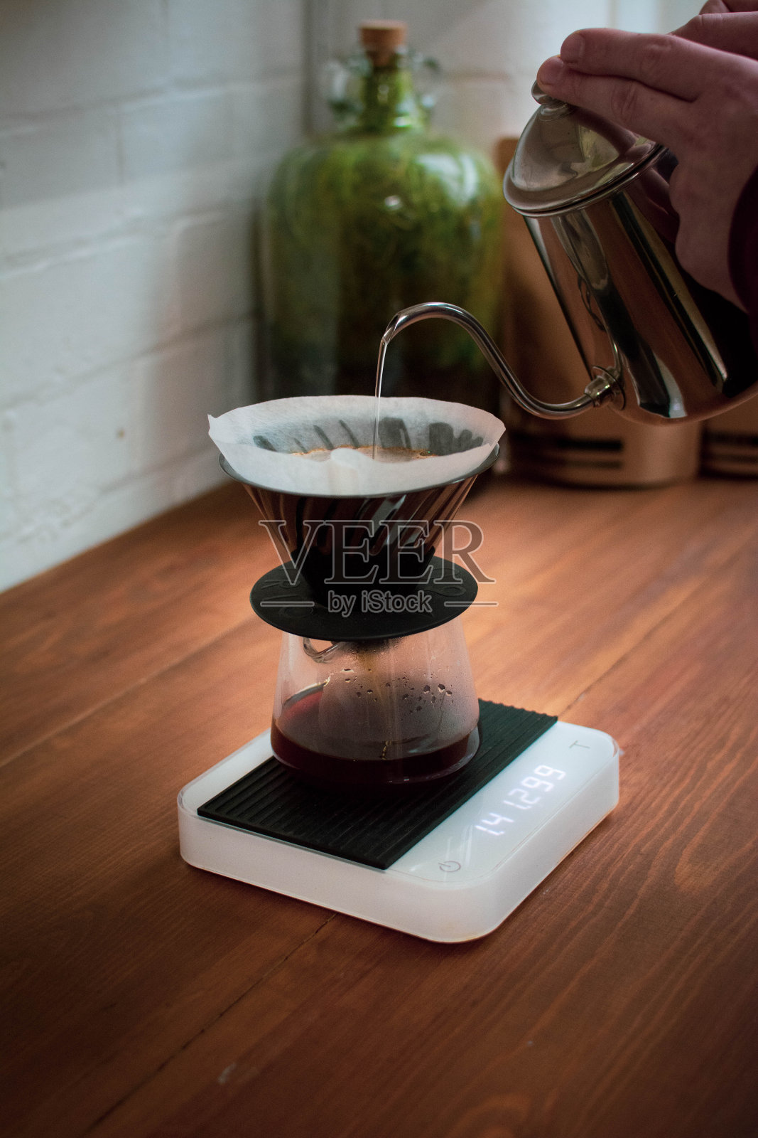 竖版照片：男人将开水倒入手冲咖啡壶照片摄影图片