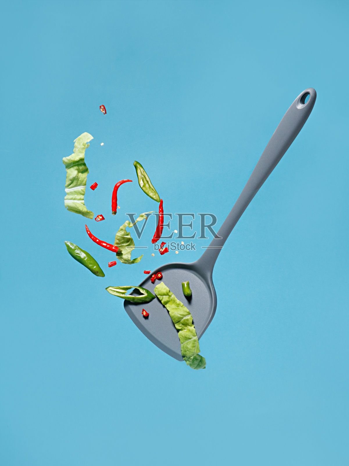 蓝色背景的绿色沙拉用勺子盛上蔬菜碎——一张美食海报照片摄影图片