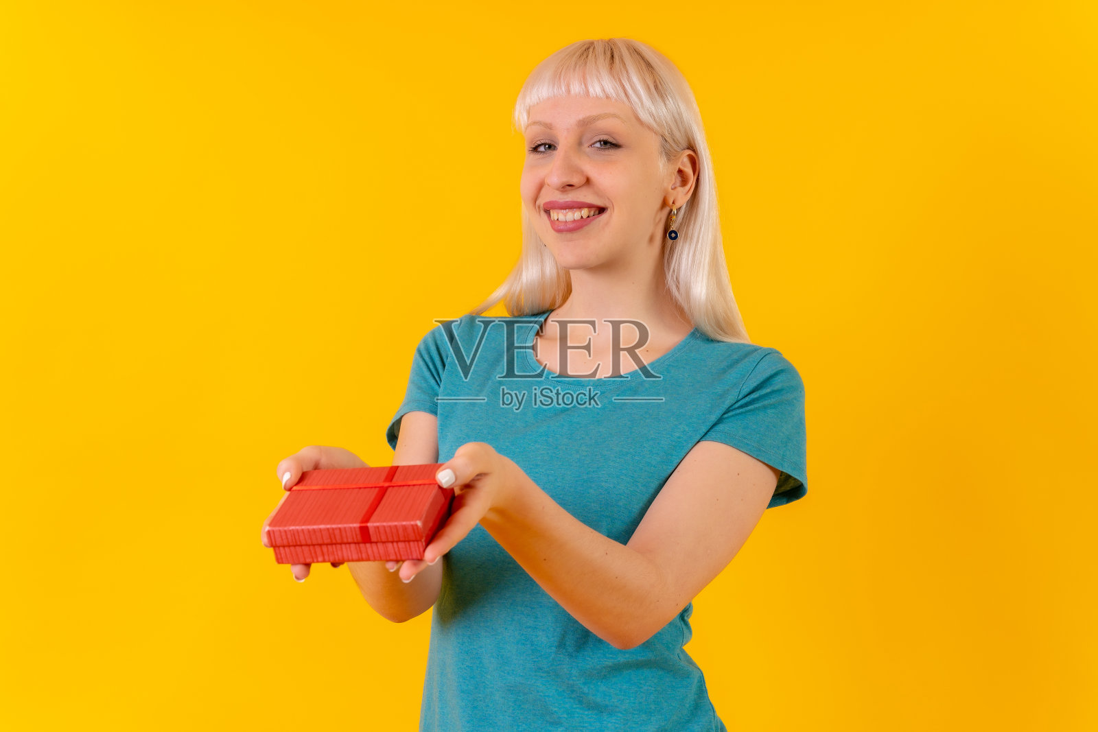 送惊喜礼物，金发白人女孩在演播室，黄色背景照片摄影图片