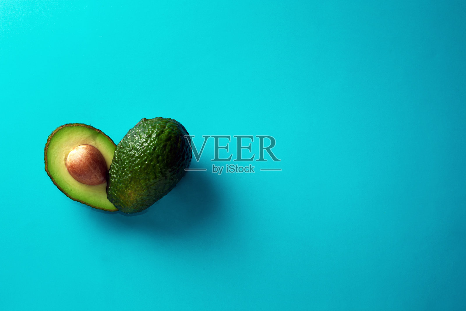 蓝色背景上有新鲜的牛油果。带有文本自由空间的横幅。健康饮食。照片摄影图片