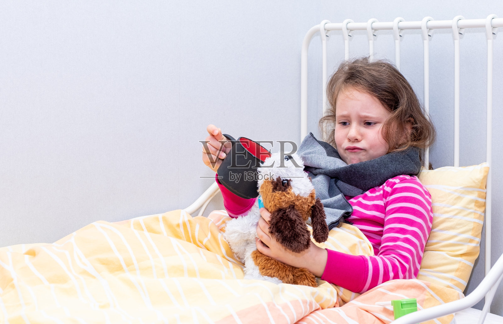 一个7岁的白人女孩生病了，躺在床上。这孩子玩软玩具。照片摄影图片