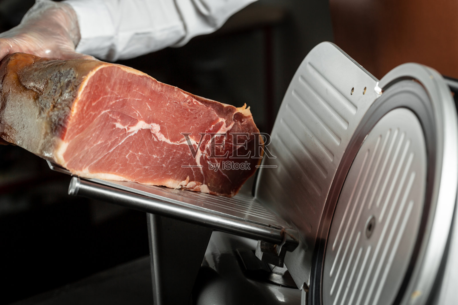 拿着意大利熏火腿或西班牙火腿的女人。开胃菜:意大利熏火腿和西班牙伊比利亚火腿照片摄影图片