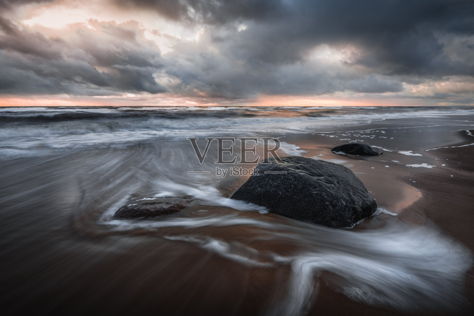 在多云的日落天空下，有许多岩石的美丽海景照片摄影图片