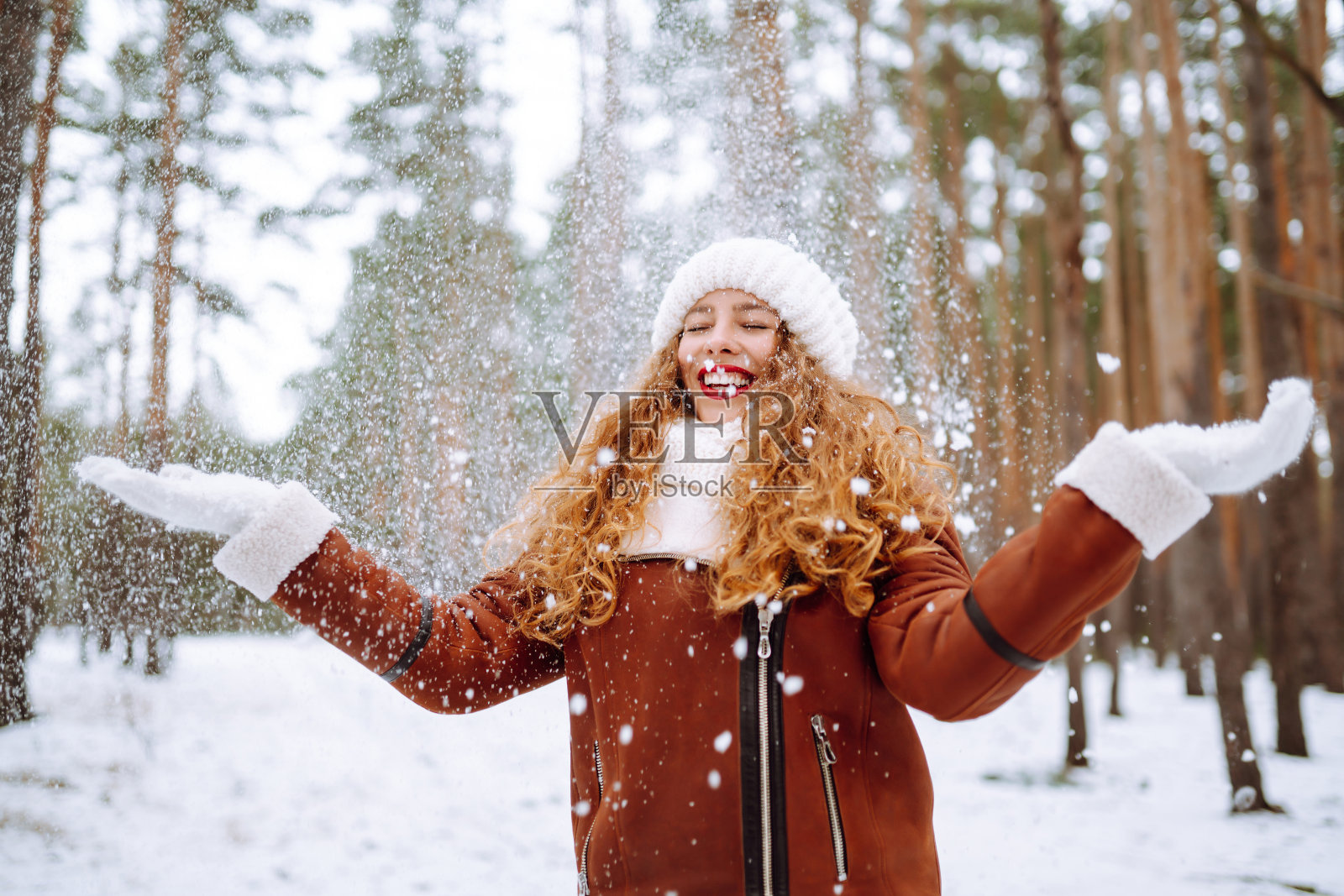 美丽的女人站在雪树和享受初雪。照片摄影图片