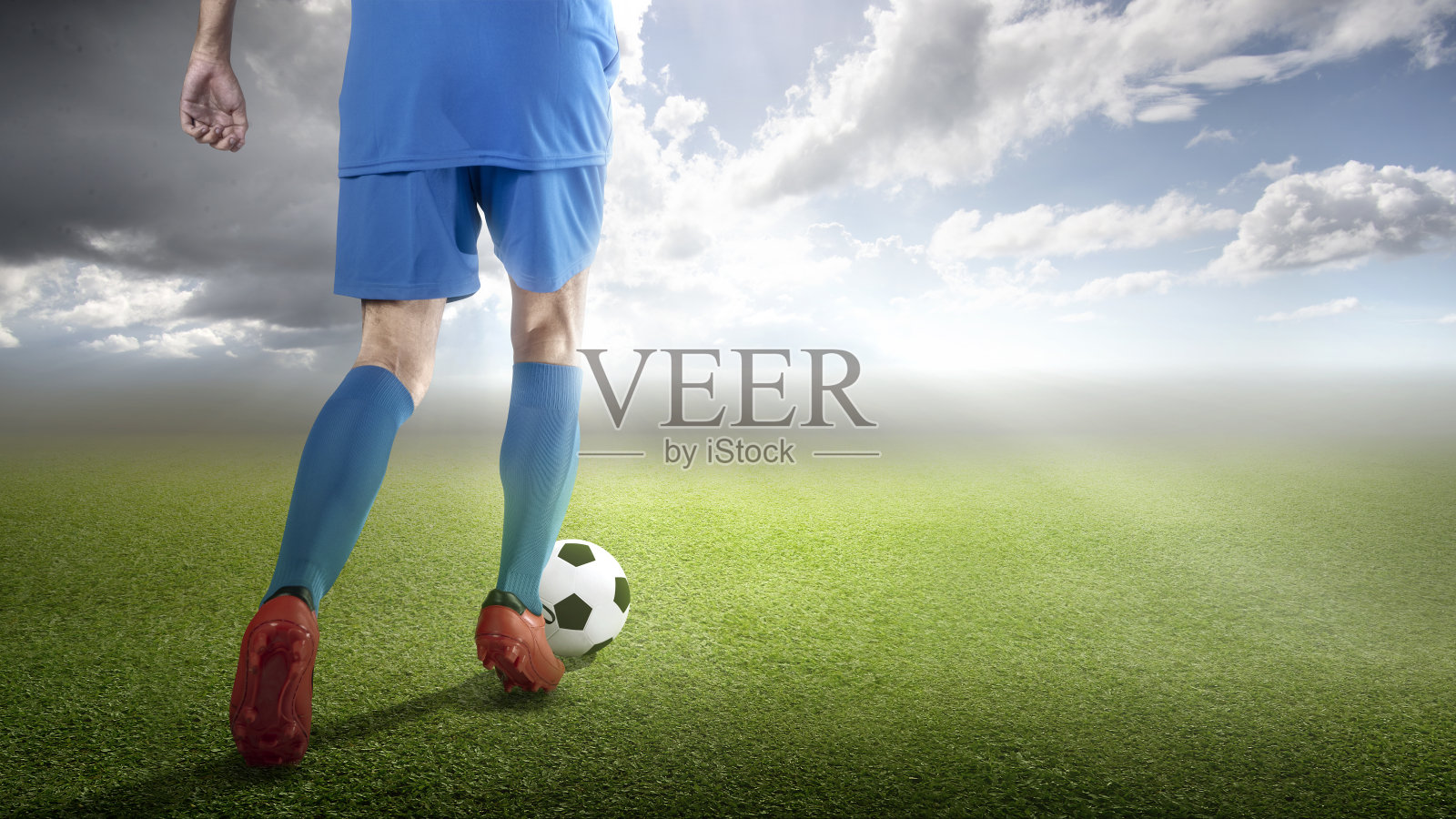 一个穿着蓝色球衣的足球运动员正在带球照片摄影图片