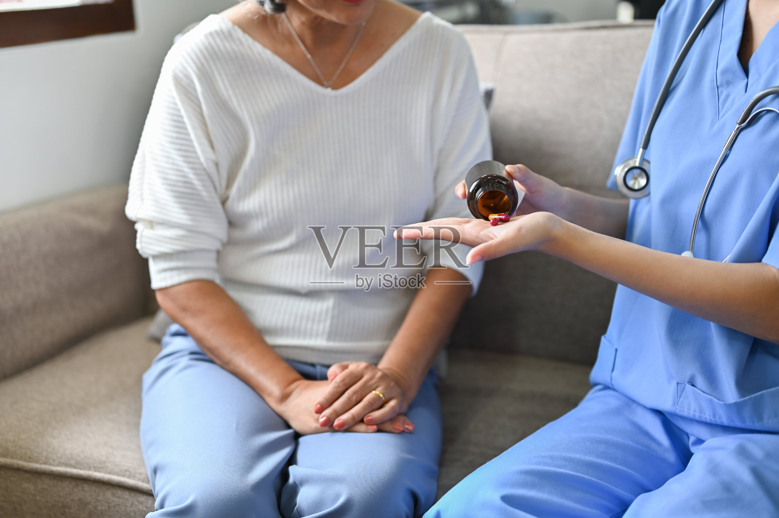 给老年妇女吃药的女护士或护理人员。照片摄影图片