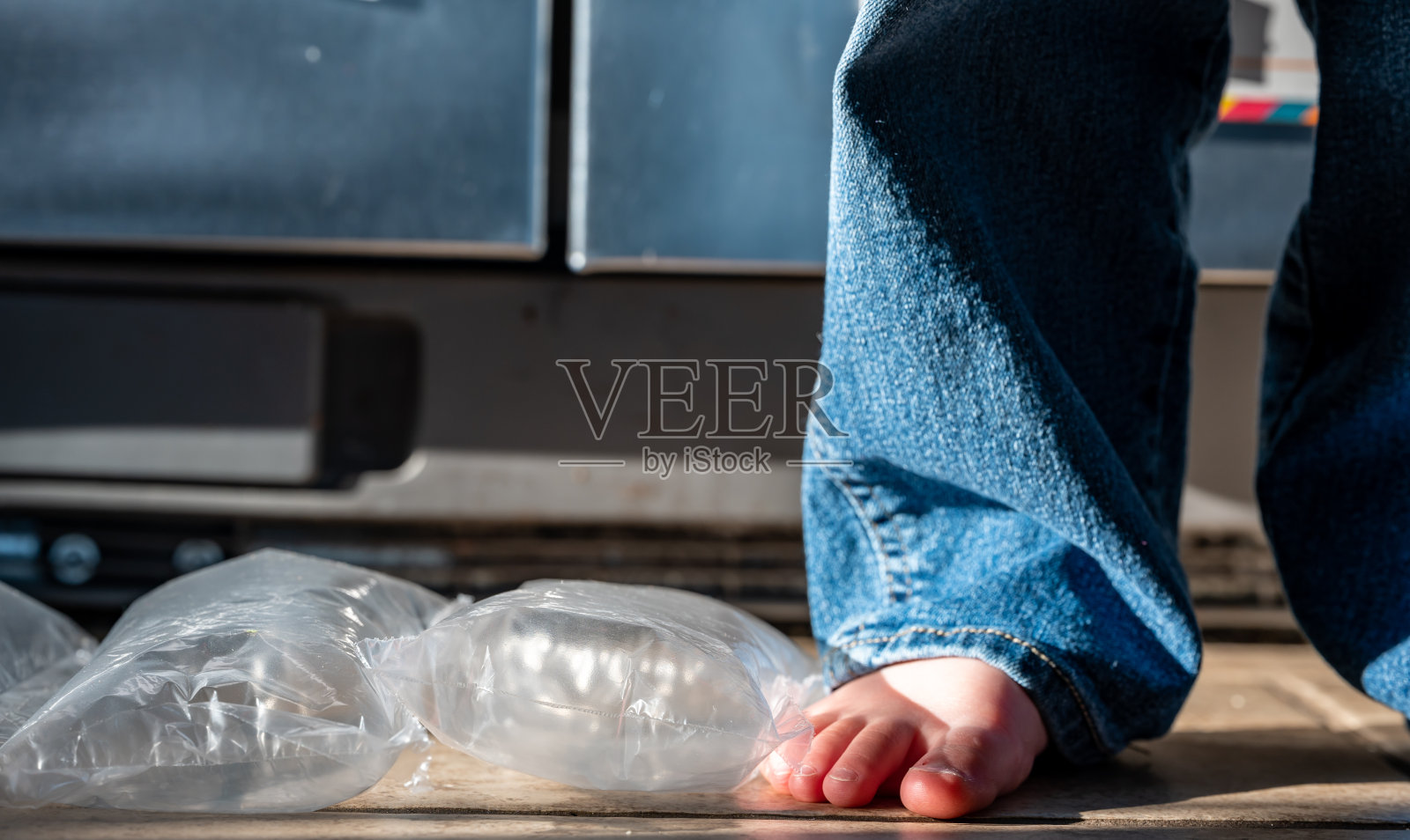 聚焦站在已爆破气泡膜上的儿童的脚照片摄影图片