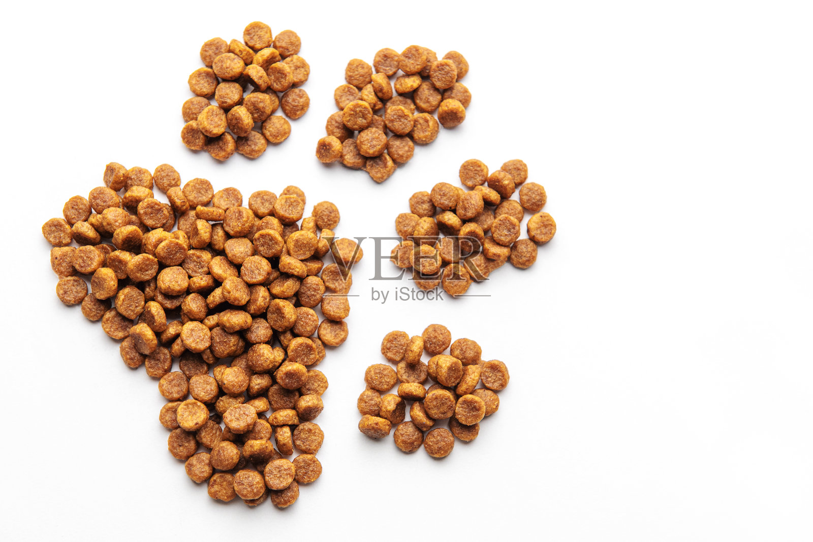 狗的爪印是由白色背景上的狗粮颗粒组成的。照片摄影图片