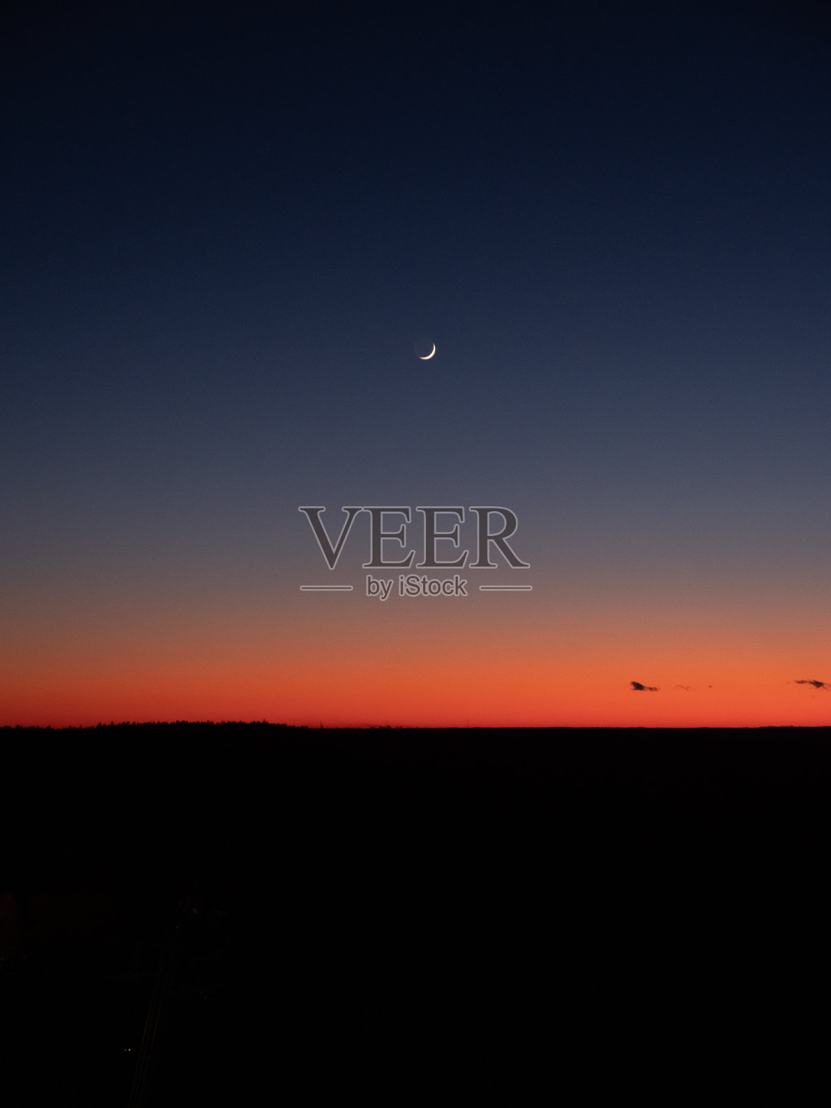 傍晚日落时天空中新月的垂直视图。照片摄影图片