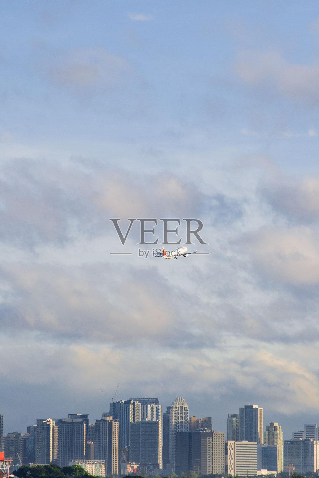 垂直拍摄的一架飞机飞过有美丽摩天大楼的城市照片摄影图片