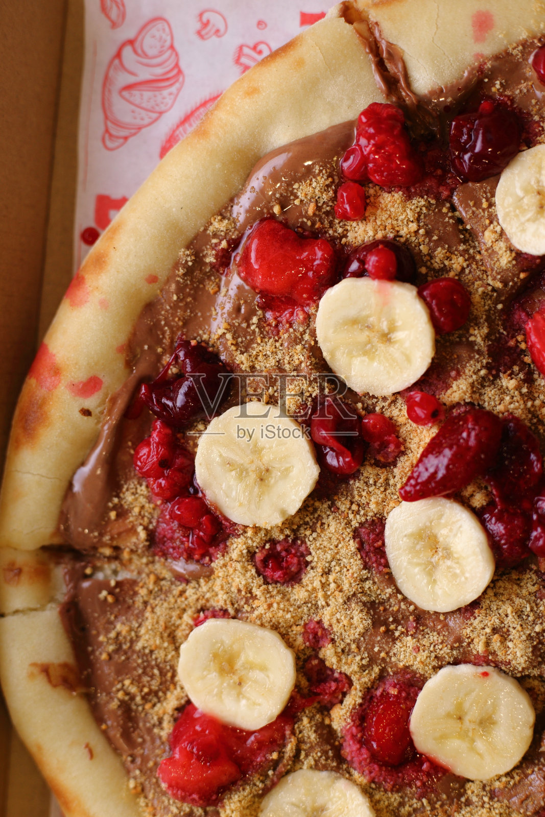 垂直顶视图的巧克力蔓延覆盖披萨面团与香蕉，草莓和榛子照片摄影图片