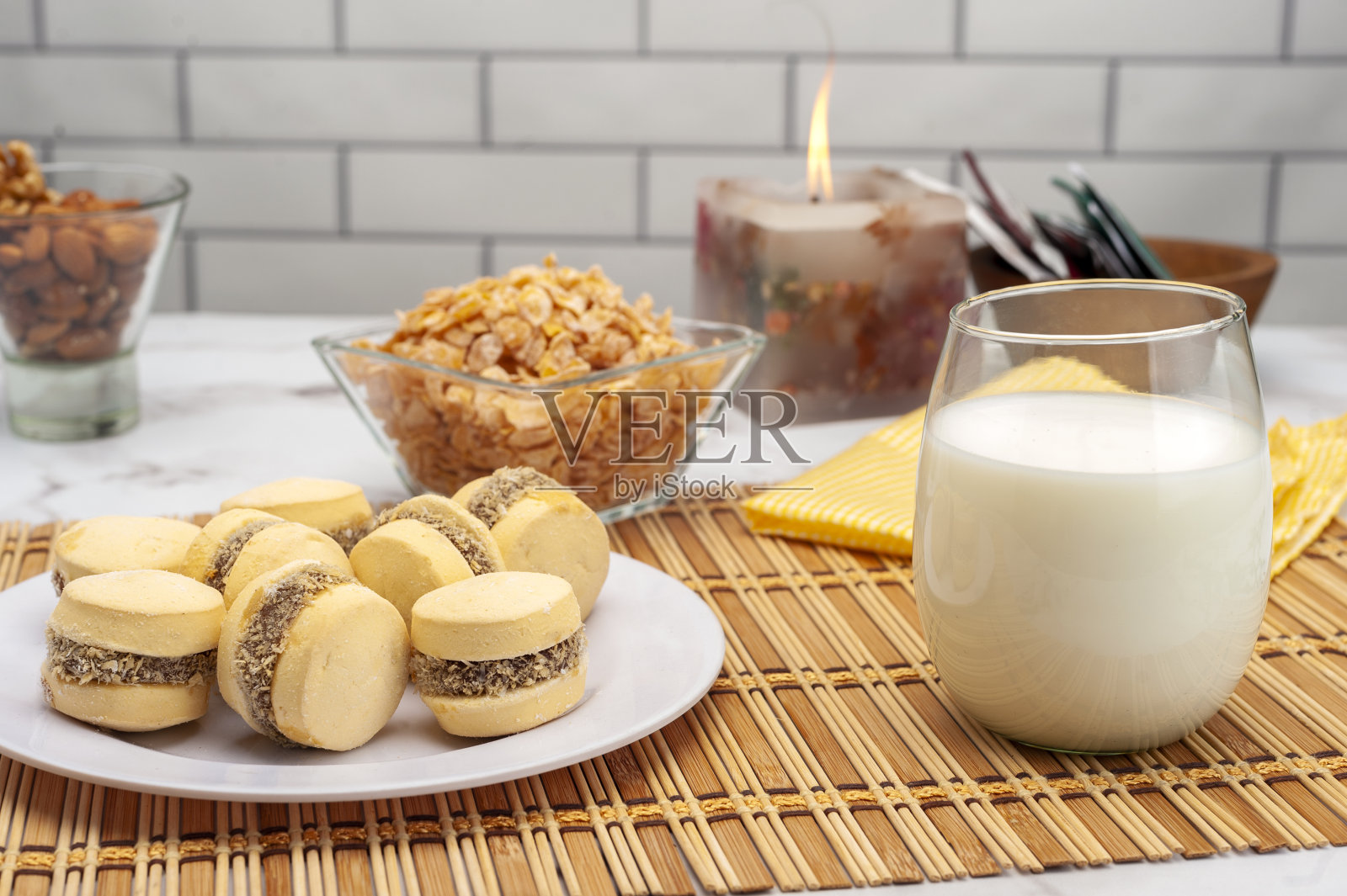 特写镜头:一杯牛奶旁边放着桌上的一些饼干和糖果。照片摄影图片
