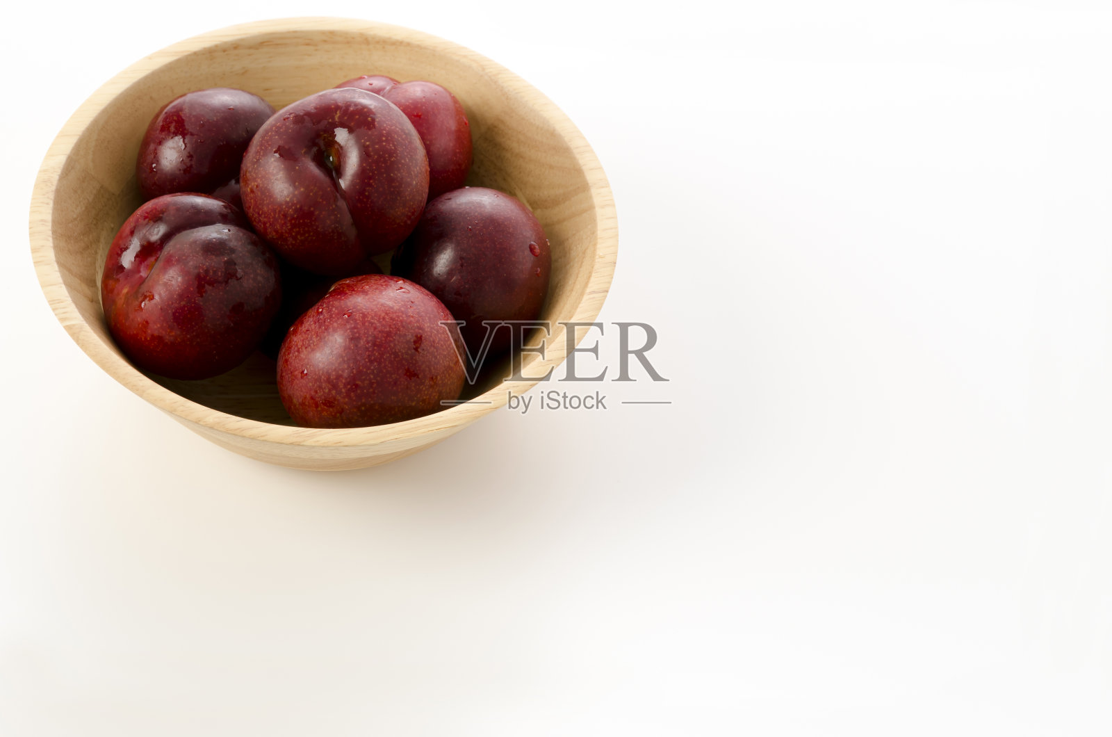 日本李子(Prunus salicina)，放在白色背景的圆木碗里照片摄影图片