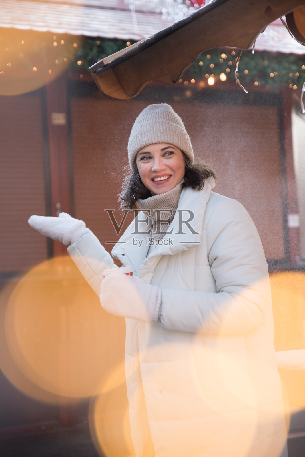 公平的。女孩穿着白夹克，戴着白帽子。女孩笑了。手里拿着一杯咖啡。木制避暑别墅。女孩喜悦。的情绪。照片摄影图片