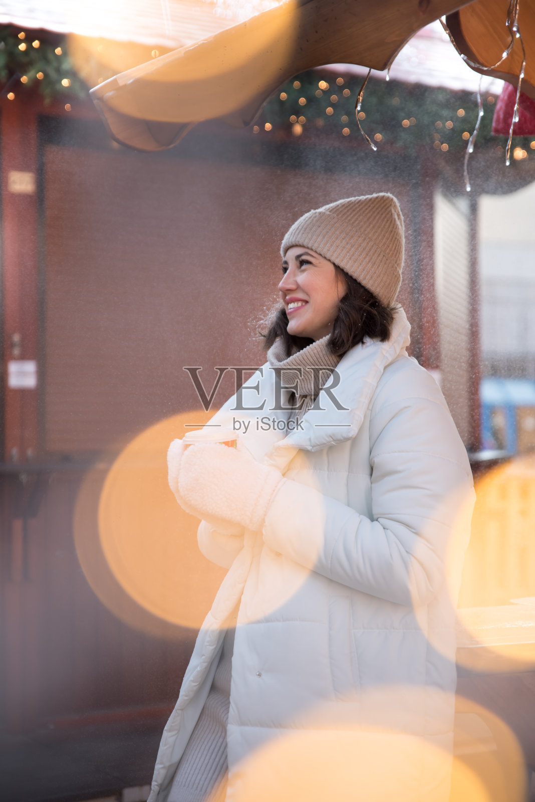 公平的。女孩穿着白夹克，戴着白帽子。女孩笑了。手里拿着一杯咖啡。木制避暑别墅。女孩喜悦。的情绪。照片摄影图片