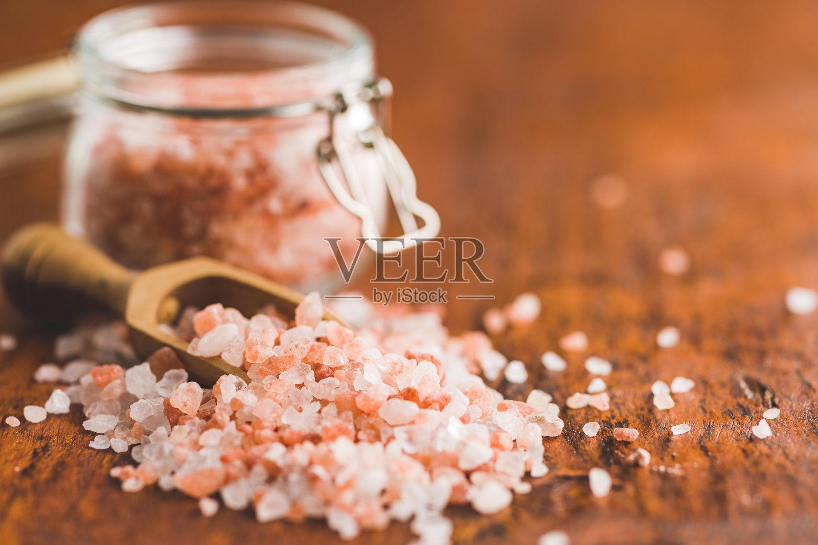 木桌上放着粉红色的喜马拉雅盐。照片摄影图片