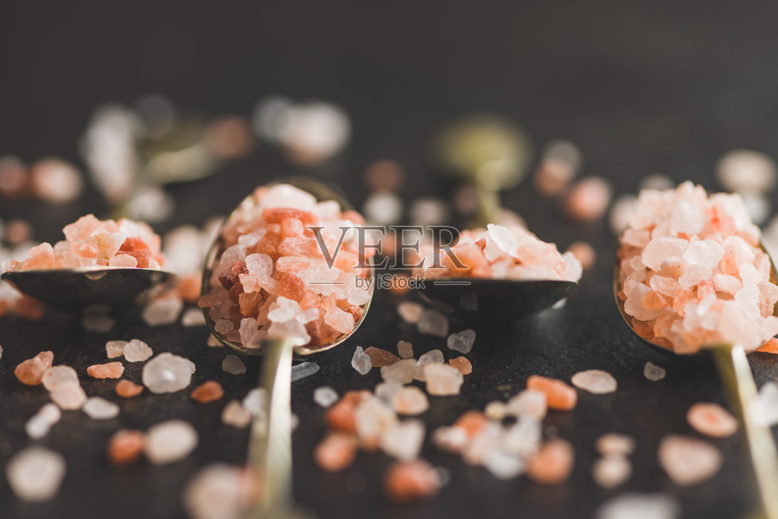 粉红色的喜马拉雅盐在黑色的桌子上。照片摄影图片