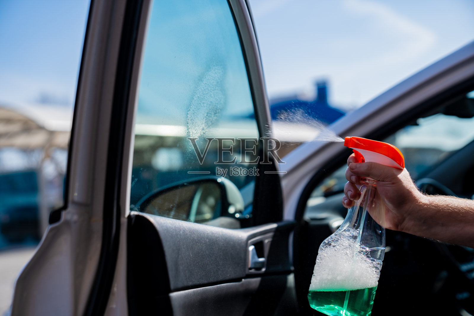 自助洗车。一个男人正在用玻璃清洗液清洗车窗照片摄影图片