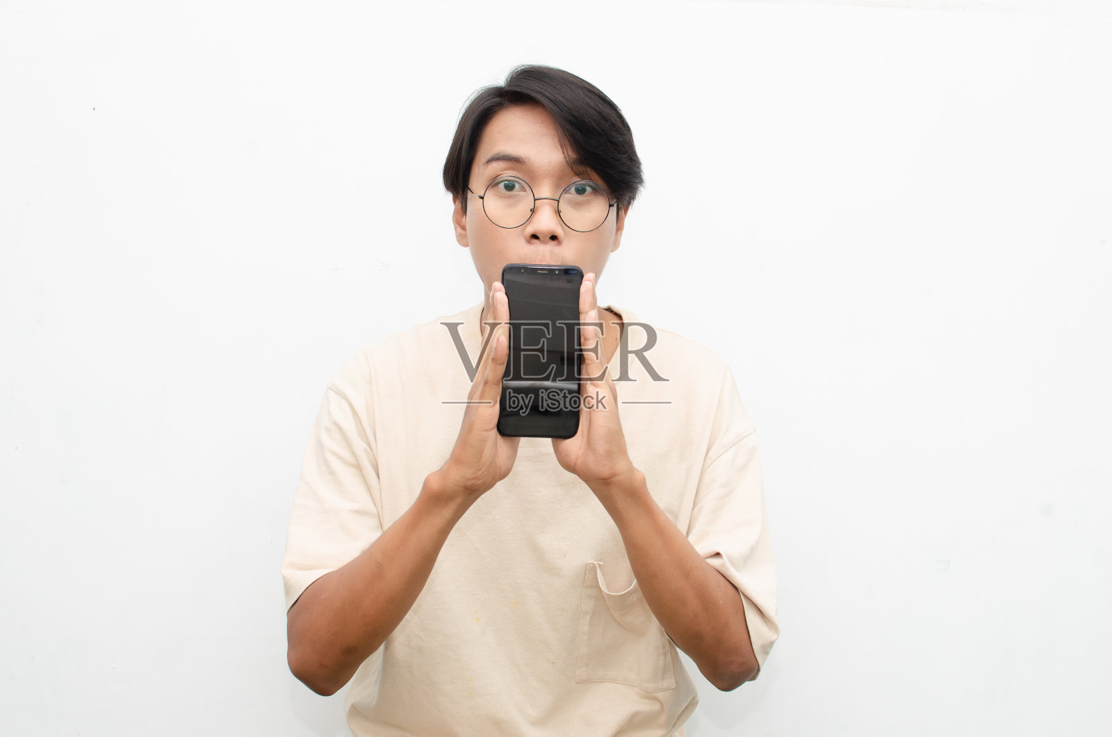 亚洲男子惊讶地看着手机屏幕。照片摄影图片