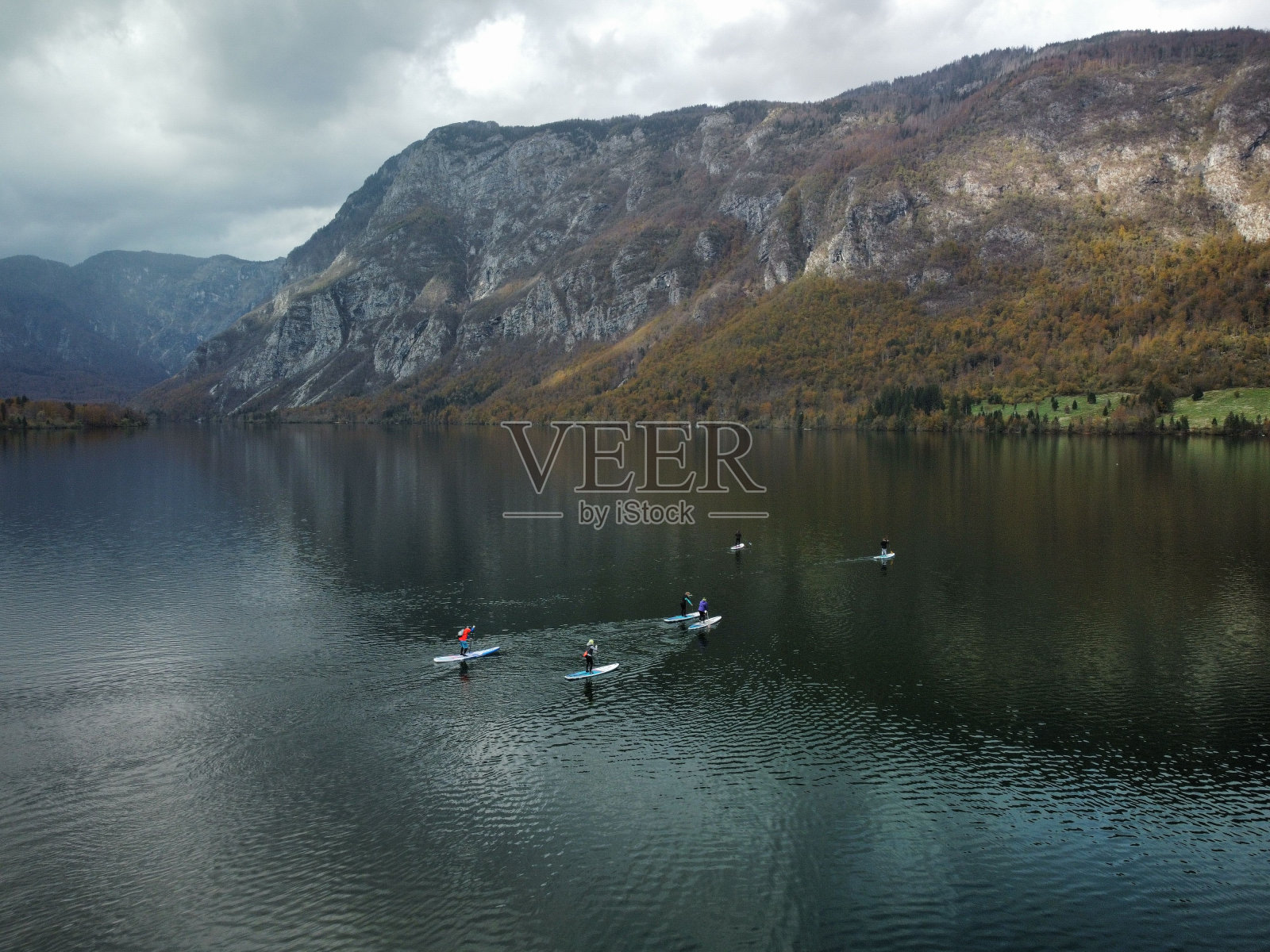 一个美丽的镜头，人们在一个被秋天颜色的山丘包围的湖中划船照片摄影图片