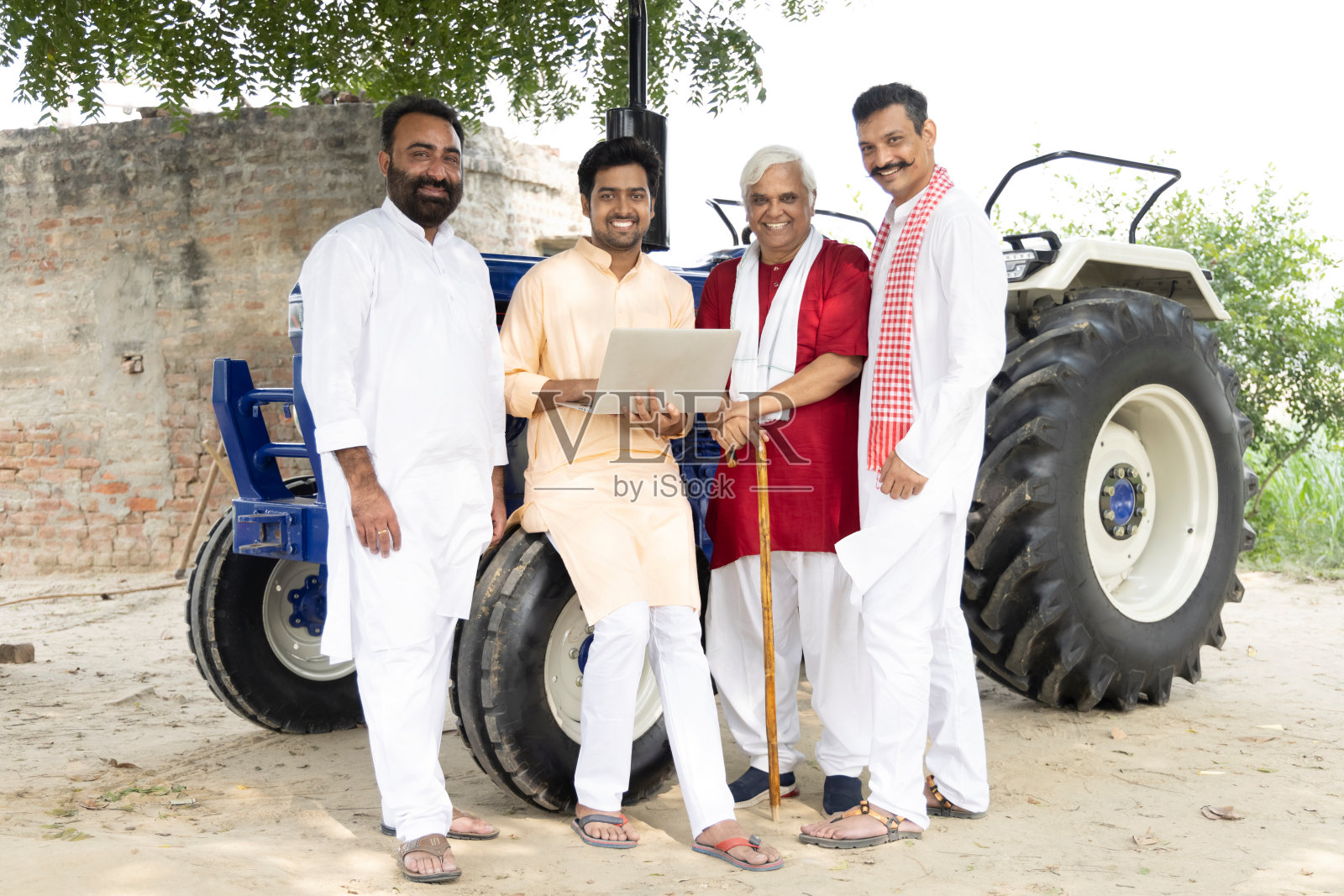 年轻人在农田里用笔记本电脑指导农民学习现代农业技术。照片摄影图片