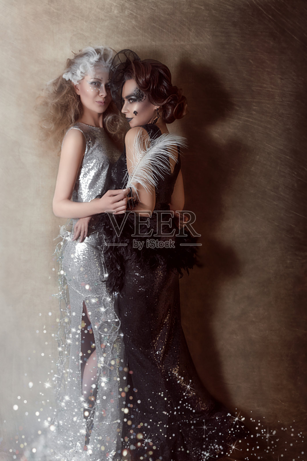 黑天鹅和白天鹅。两个美丽的女孩，长着羽毛的黑白天鹅。艺术摄影。照片摄影图片