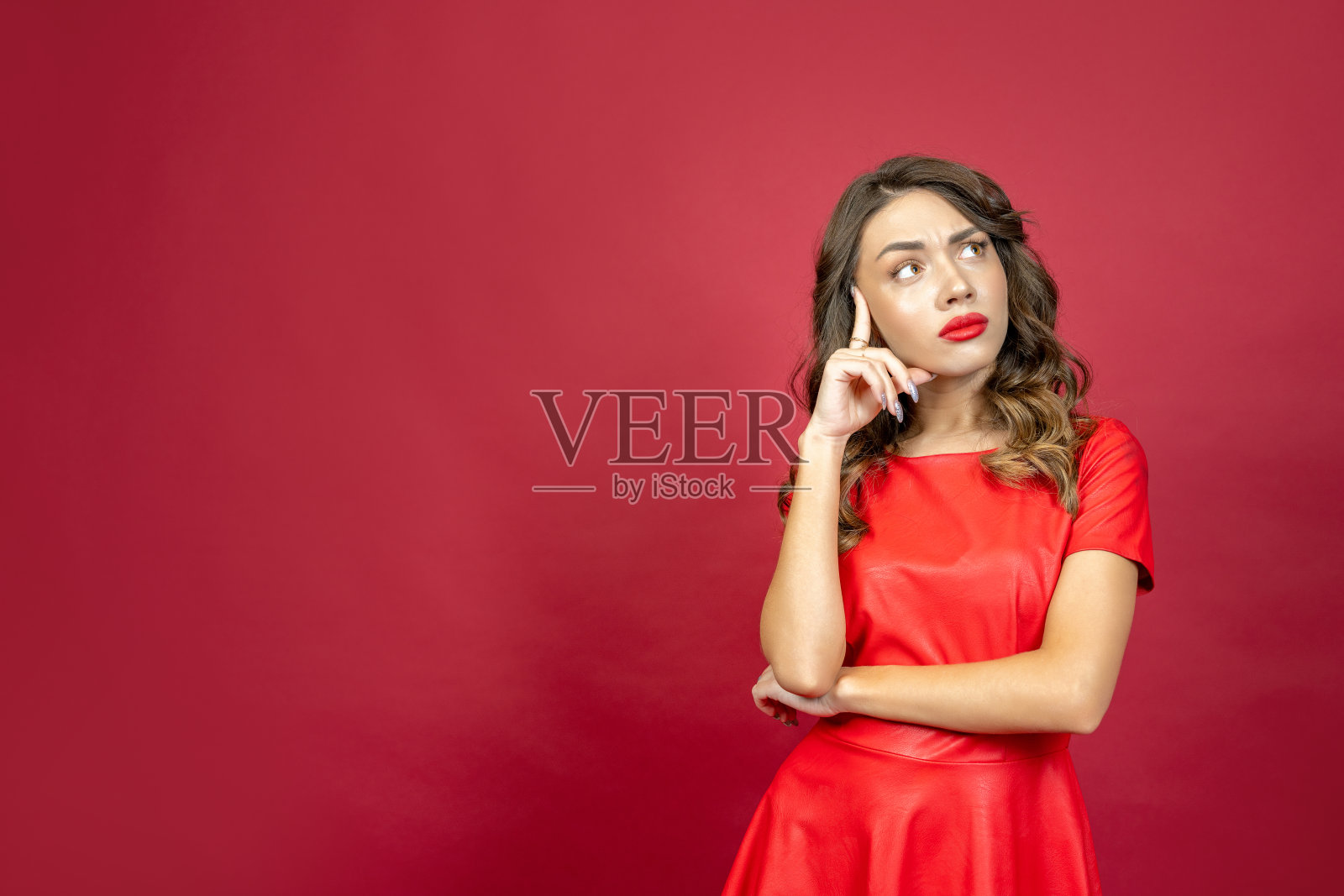 一名女子若有所思地看着红色背景照片摄影图片