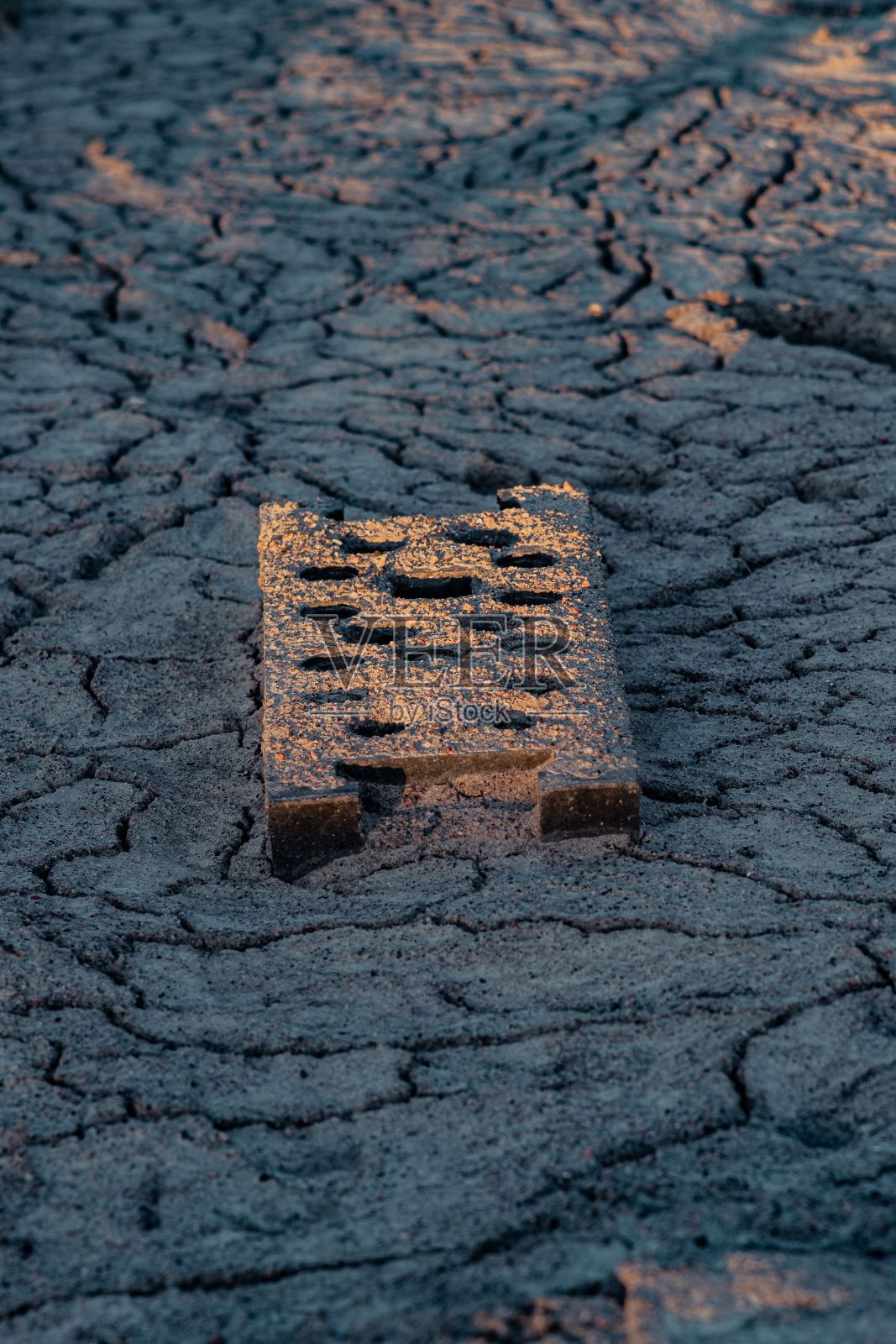 垂直特写镜头的一个建筑块在干燥，干旱的地面上照片摄影图片