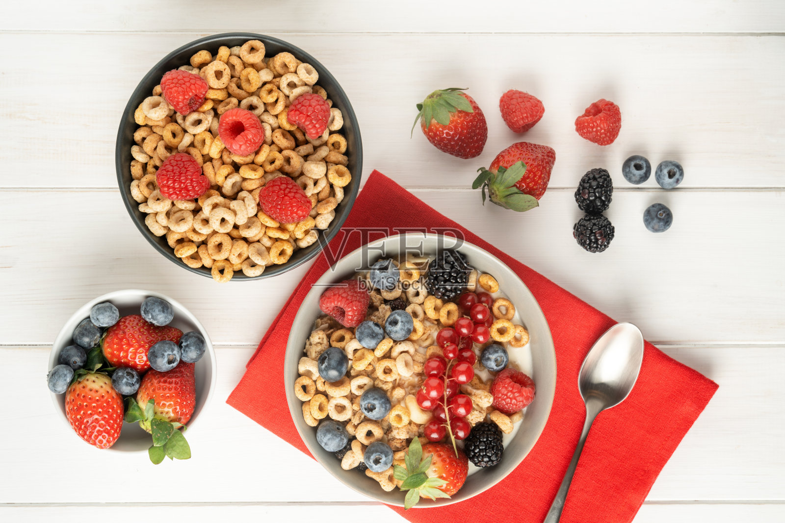 白色桌子上的红餐巾上放着盛着浆果的麦片碗，俯视图照片摄影图片