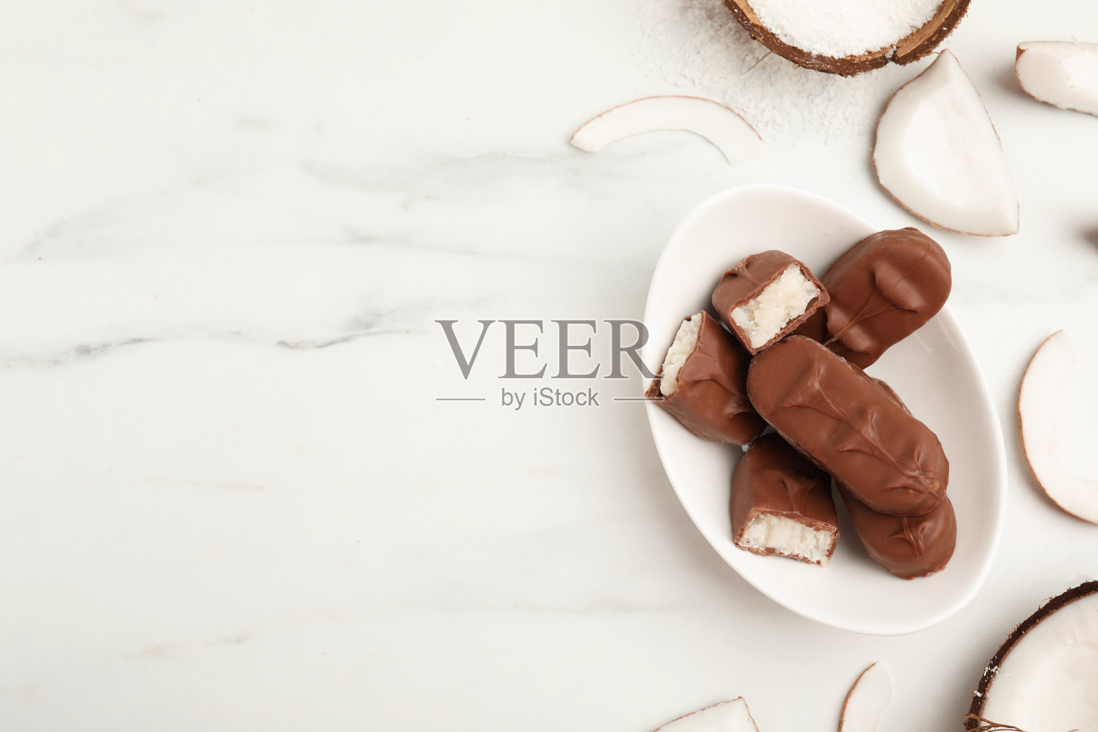 白色大理石桌上放着美味的牛奶巧克力巧克力，里面有椰子馅。文本空间照片摄影图片