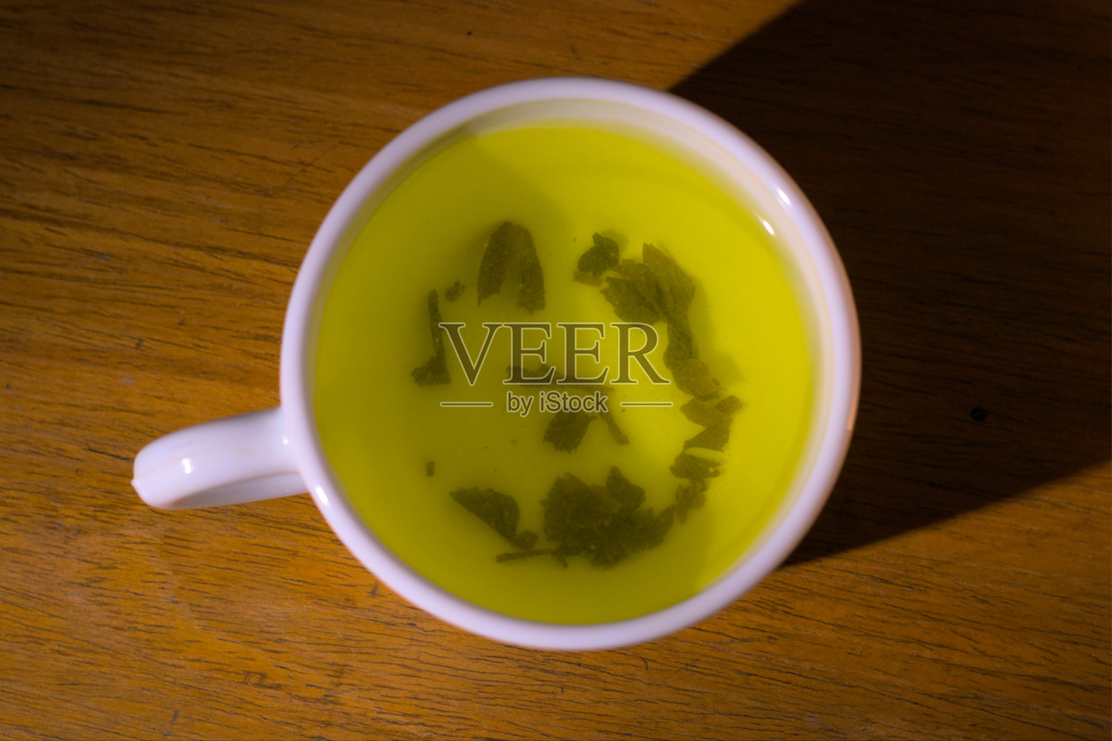 茶:桌上放有叶子的一杯花草茶或绿茶前视图。照片摄影图片