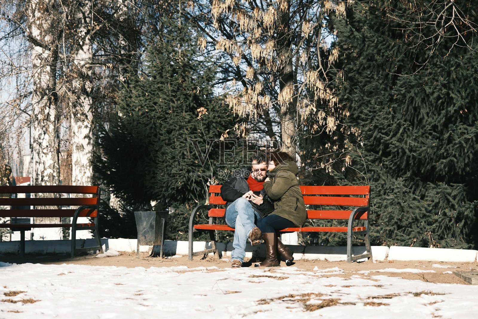 一对成熟的夫妇正坐在冬日公园的长椅上照片摄影图片