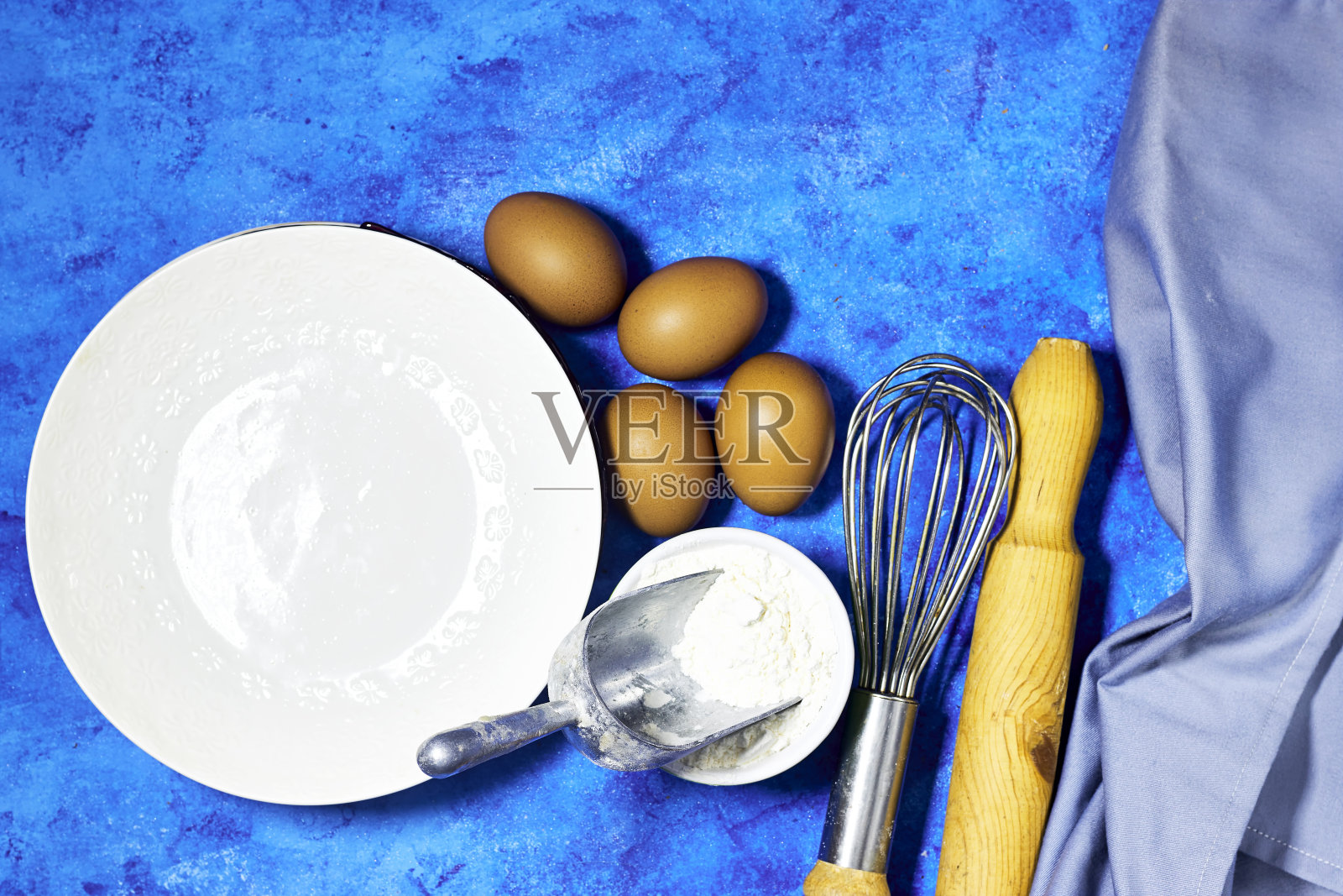 空盘子，鸡蛋和金属丝打蛋器和鸡蛋在蓝色垃圾背景照片摄影图片