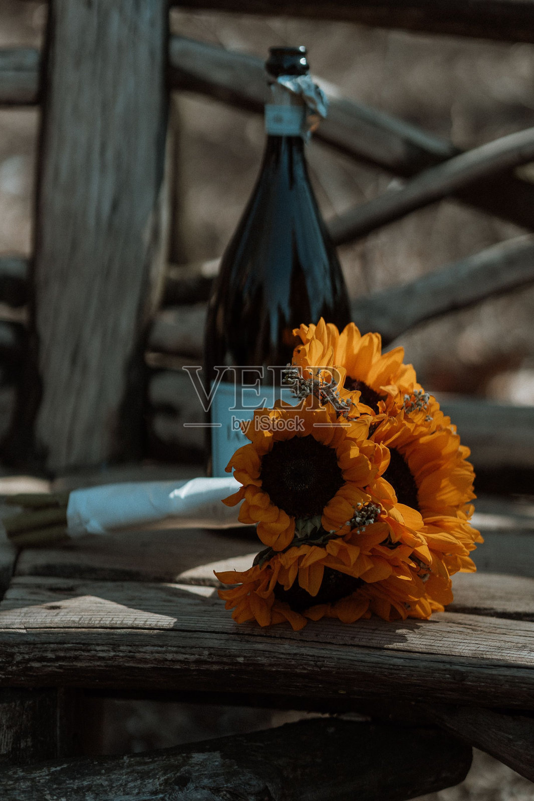 垂直拍摄的向日葵花束和香槟在木凳上照片摄影图片