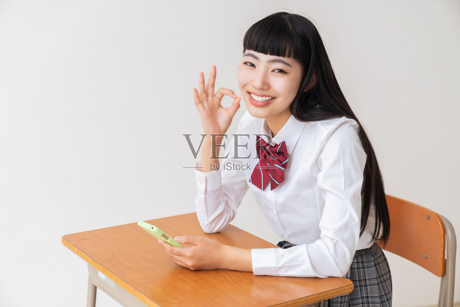 女学生使用智能手机，学校教室照片摄影图片