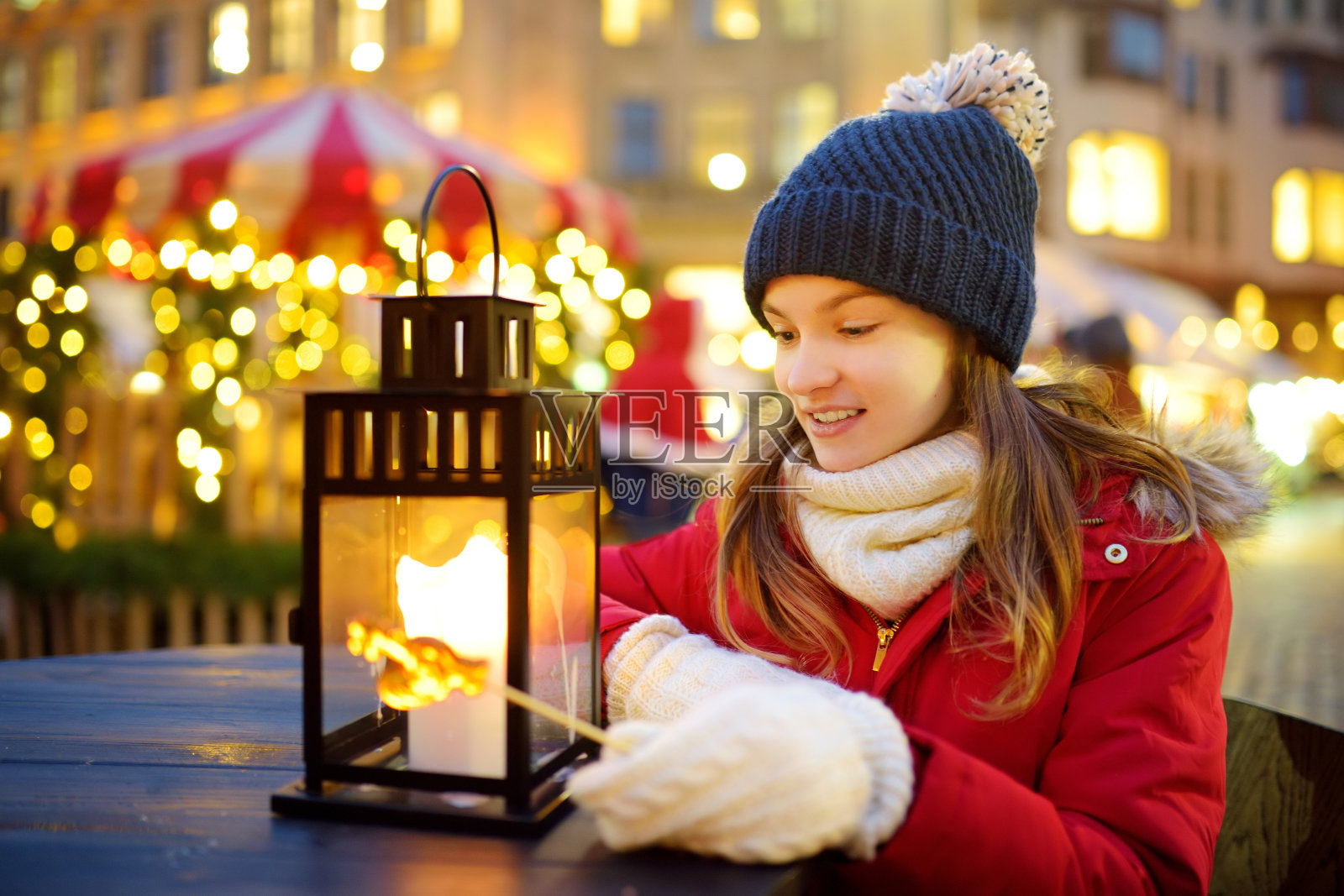 可爱的年轻女孩在拉脱维亚里加的传统圣诞集市上吃着公鸡形状的棒棒糖。孩子们在圣诞市场上享受糖果、糖果和姜饼。照片摄影图片
