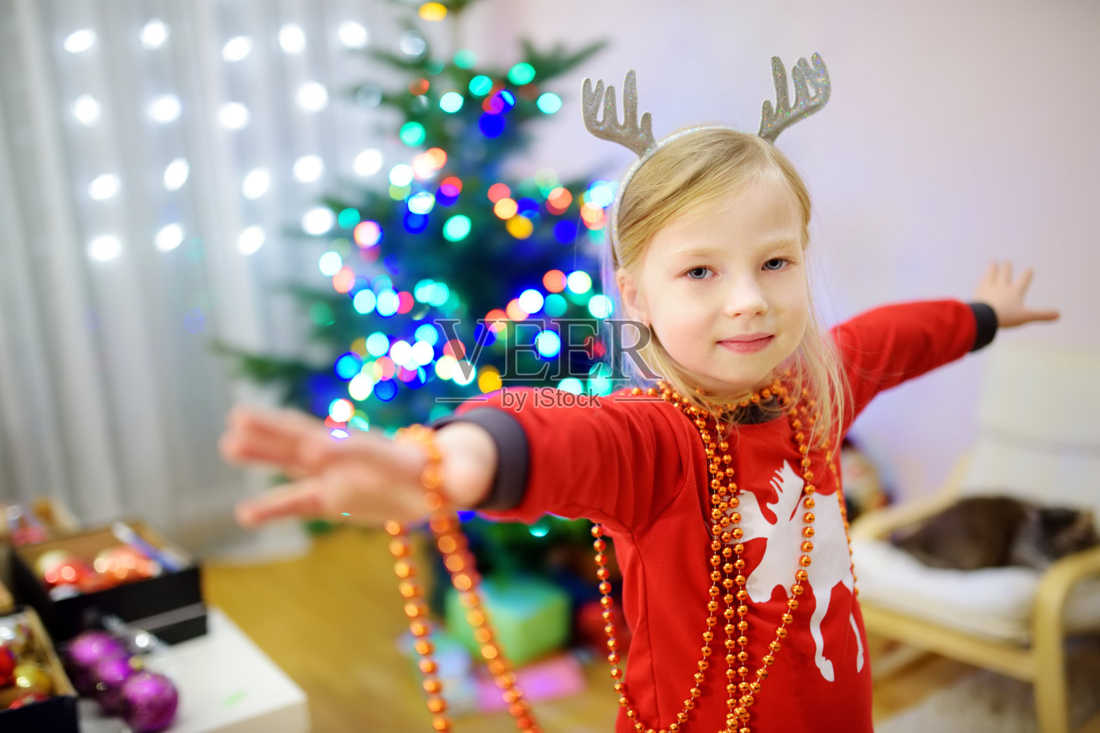 可爱的小女孩用彩色的玻璃装饰物装饰圣诞树。装饰圣诞树。照片摄影图片